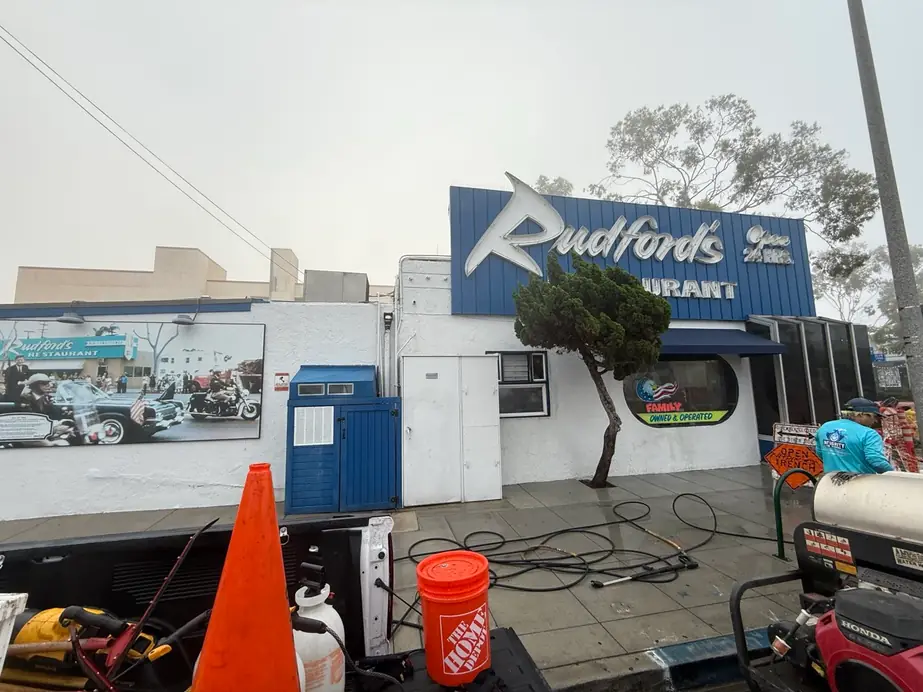 Hose reels, cones and a bucket set out along a storefront during a wash
