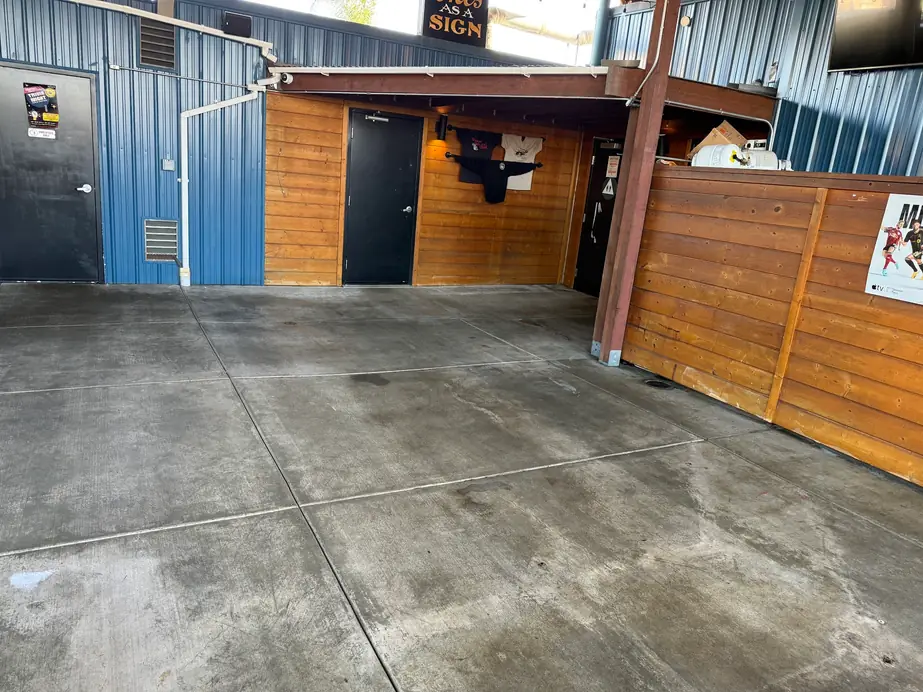 Washed concrete patio slab beside blue lap siding and a wooden fence