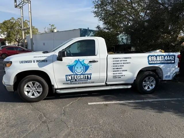 White Silverado with the Integrity Pro Washers logo, Licensed & Insured on the door and the service list on the bed